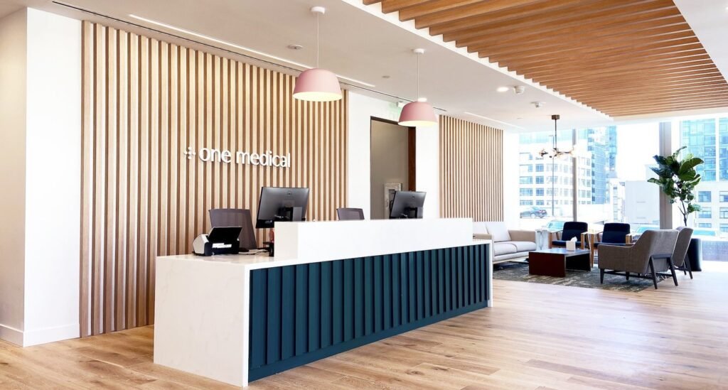 Reception area at One Medical Primary Care Clinic Pike & 2nd Clinic in Seattle with wood paneling, pendant lighting, and modern furnishings