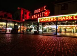 Evening view of Pike Place Market with illuminated Public Market Center sign and bustling crowd